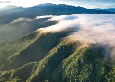 Aerial view of the Braulio Carrillo National Park, shows the green canopy partly covered with clouds. Turrialba and Irazú volcanoes can be seen in the background