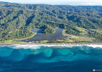 View of Carate Beach. The picture shows an empty beach and blue ocean and a small lagoon surrounded by the jungle.